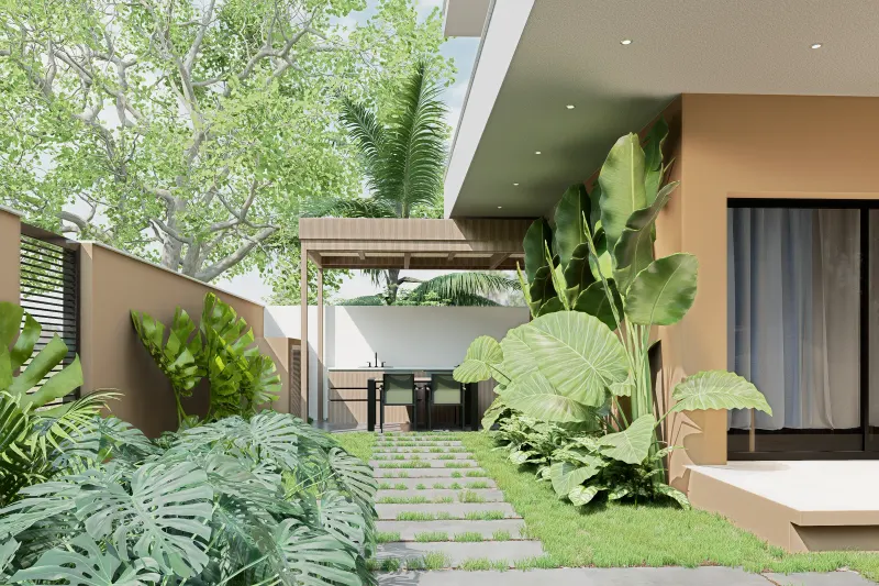 Caminho pedonal em relva ladeado por jardim tropical até à pérgula gourmet.