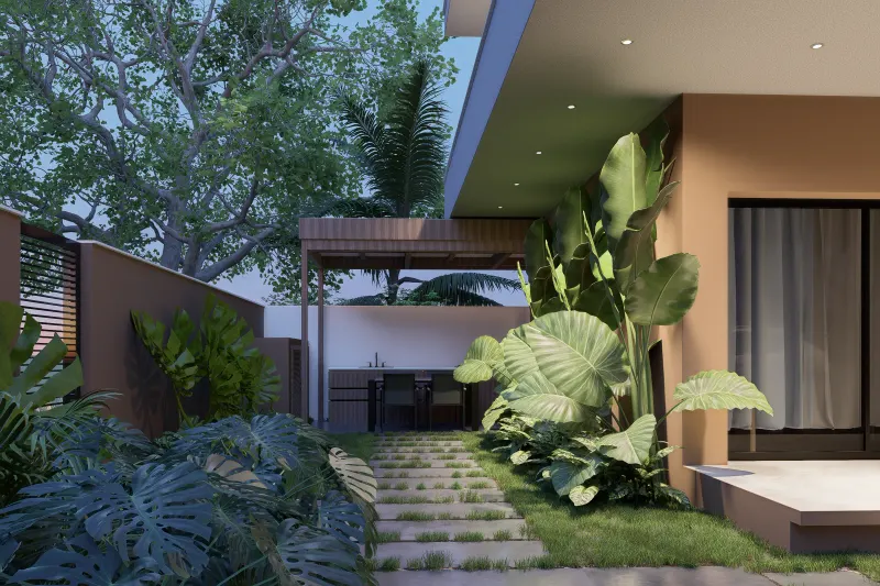 Jardim lateral tropical iluminado ao entardecer com caminho até à área gourmet.